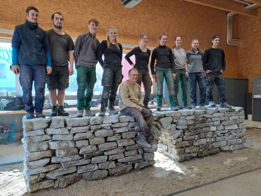 Die Schüler*innen mit Schwerpunkt Gartengesaltung präsentieren ihre Mauer aus Naturstein, die sie im Mauerbauseminar gebaut haben