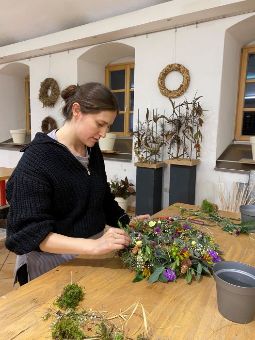 Eine Abenschülerin perfektioniert ihr Können im Praxisunterricht Floristik bei einem gesteckten Kranz