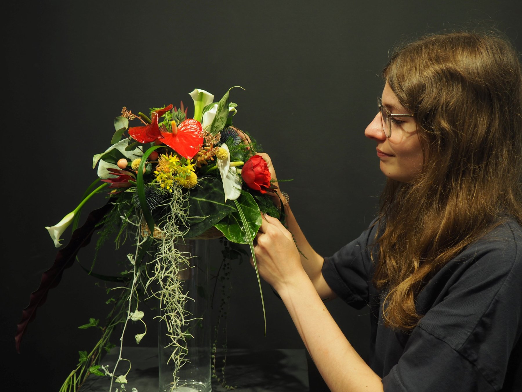 Eine Schülerin der 4. Klasse mit dem Schwerpunkt Floristik betrachtet ihren formal-linearen Brautschmuck, den sie im Praxisunterricht gebunden hat
