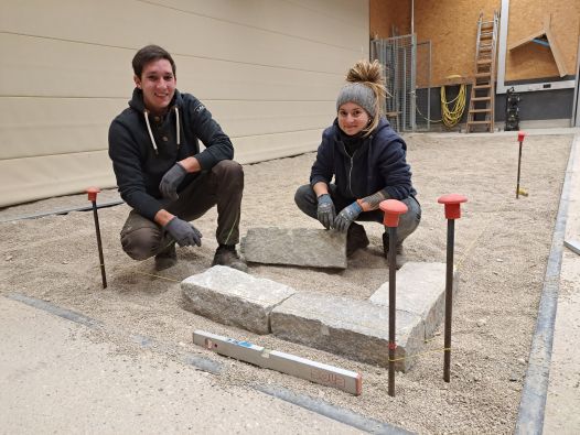 Zwei Abendschüler*innen haben die ersten drei Leistensteine aus Granit eingerichtet